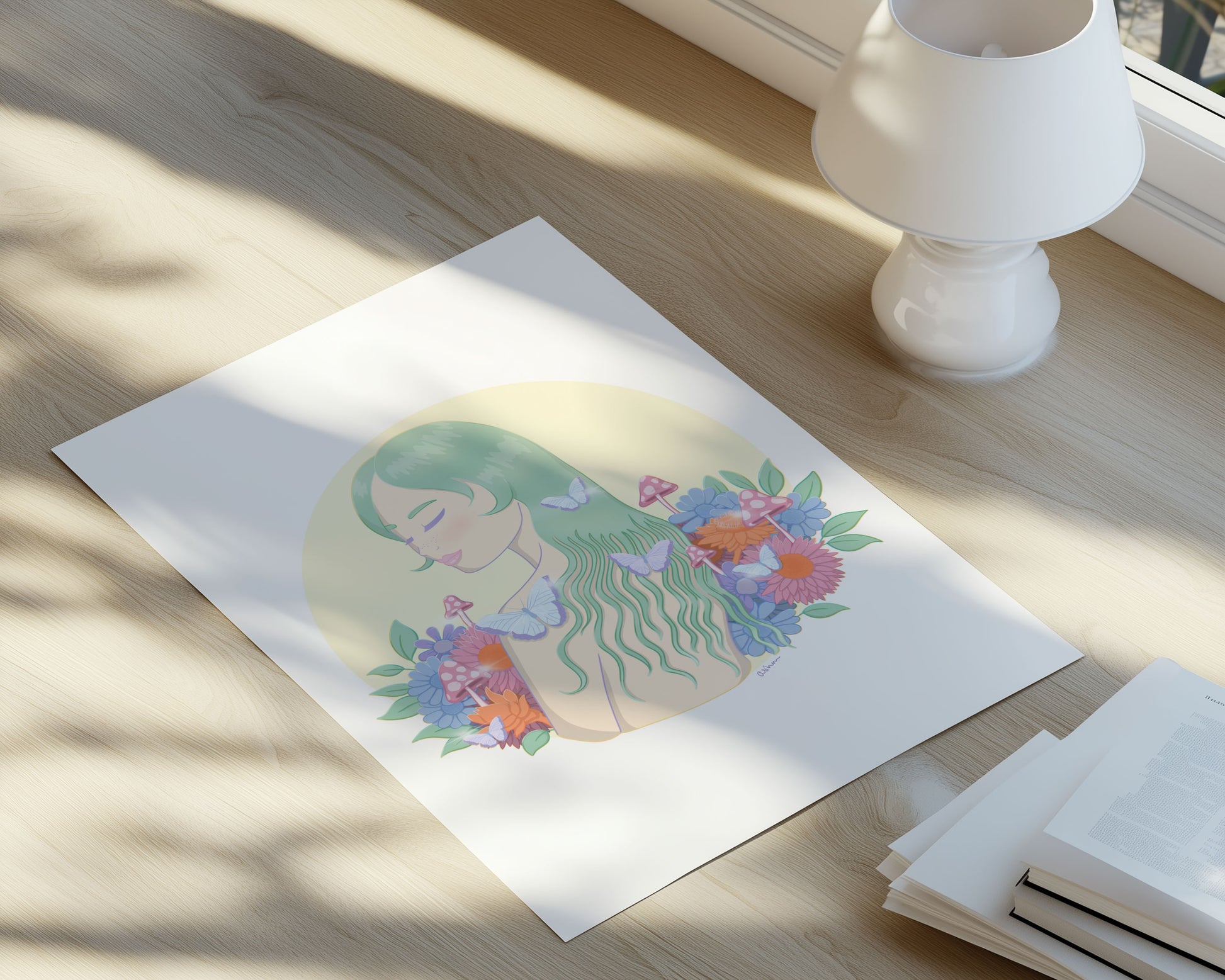 Illustration of a woman with flowers in her hair, surrounded by flowers and mushrooms. The print is on a timber surface with a lamp in the background.