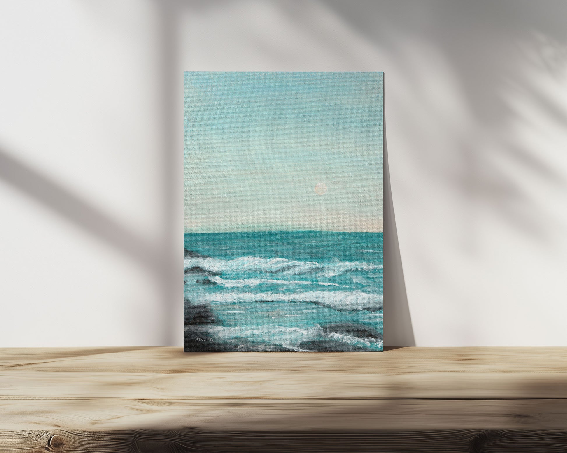 Painting of an ocean, blue water and waves with whitewash and a moon in the sky. 